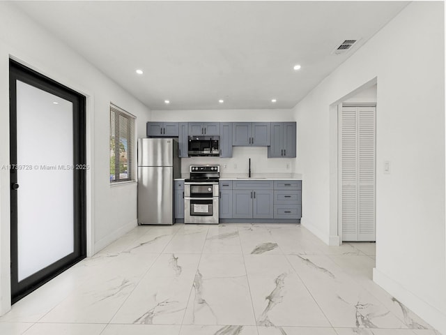 kitchen with appliances with stainless steel finishes, sink, and gray cabinetry