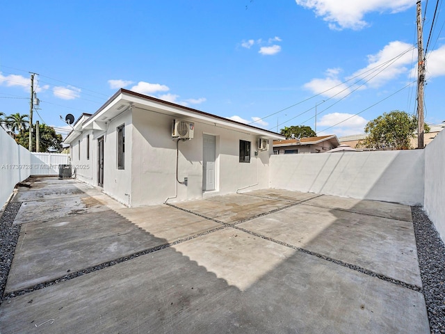 back of house featuring a wall mounted air conditioner, a patio area, and central air condition unit