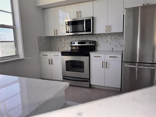 kitchen featuring light tile patterned floors, decorative backsplash, white cabinets, and appliances with stainless steel finishes