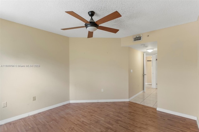 spare room with ceiling fan, a textured ceiling, and light wood-type flooring