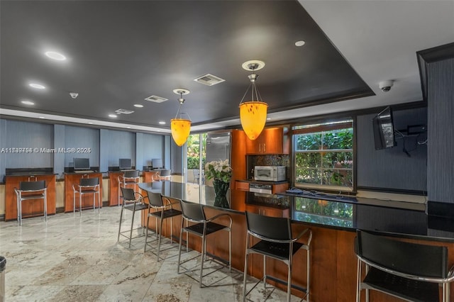 kitchen featuring plenty of natural light, a breakfast bar, pendant lighting, and a tray ceiling