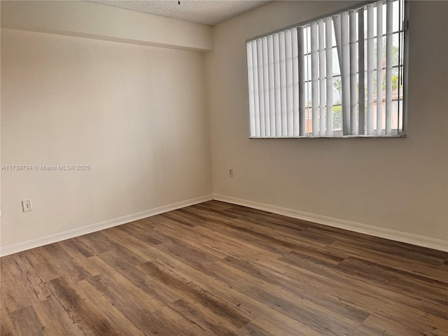 empty room featuring dark hardwood / wood-style floors and a textured ceiling