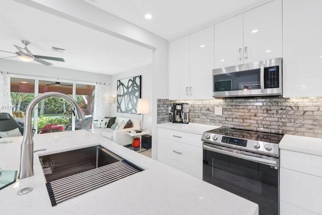 kitchen featuring sink, white cabinets, ceiling fan, stainless steel appliances, and backsplash