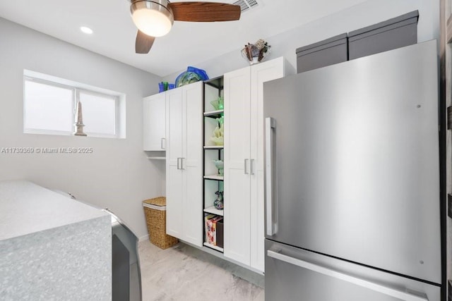 kitchen featuring ceiling fan, stainless steel refrigerator, and white cabinets