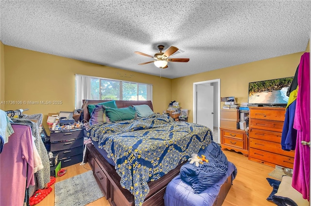 bedroom with ceiling fan, a textured ceiling, and light wood-type flooring