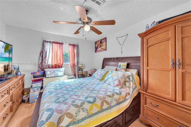 bedroom featuring ceiling fan, light hardwood / wood-style floors, and a textured ceiling