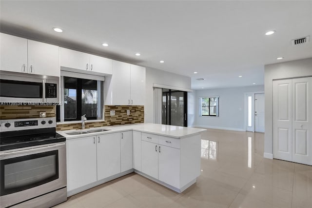 kitchen featuring appliances with stainless steel finishes, sink, white cabinets, decorative backsplash, and kitchen peninsula