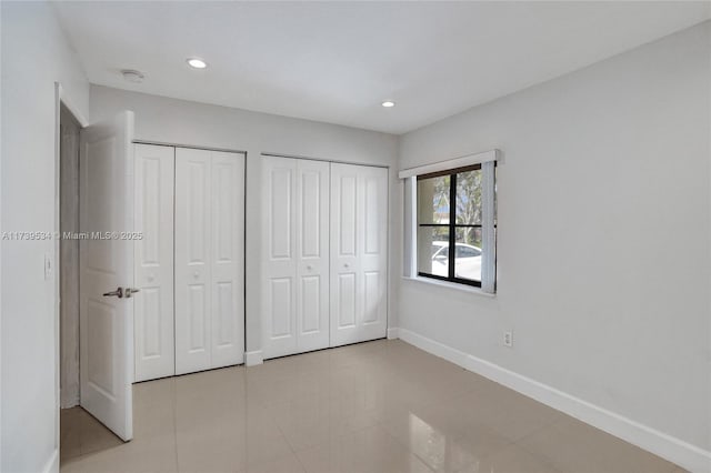 unfurnished bedroom featuring multiple closets and light tile patterned floors