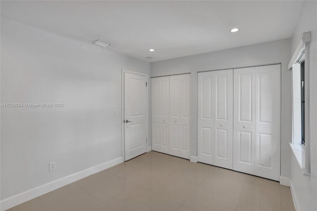 unfurnished bedroom with two closets and light tile patterned flooring