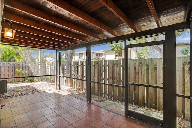 unfurnished sunroom with beamed ceiling, a healthy amount of sunlight, and wooden ceiling