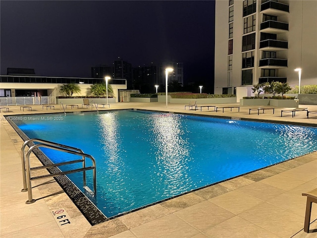 pool at night featuring a patio