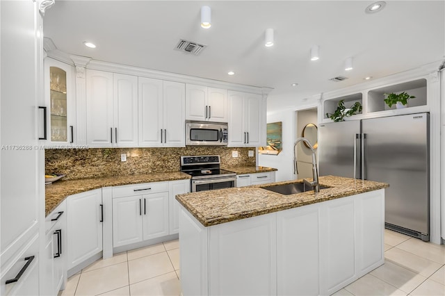 kitchen featuring light tile patterned floors, stainless steel appliances, tasteful backsplash, white cabinetry, and a sink