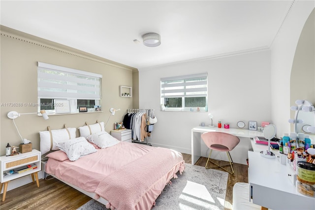 bedroom with crown molding, baseboards, and wood finished floors