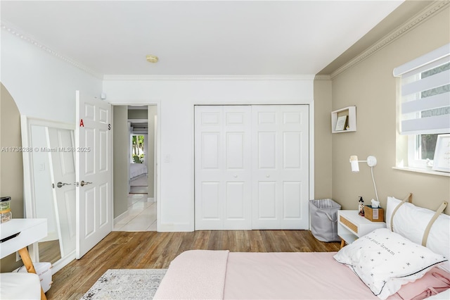 bedroom featuring ornamental molding, a closet, multiple windows, and wood finished floors