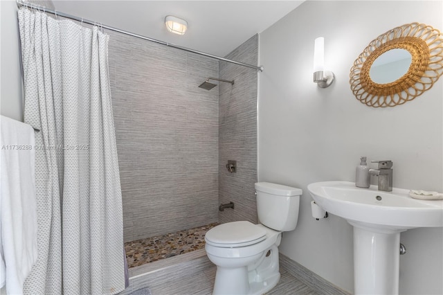 full bath featuring toilet, baseboards, and tiled shower