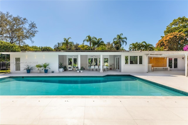 rear view of property with an outdoor pool, a patio, ceiling fan, french doors, and stucco siding