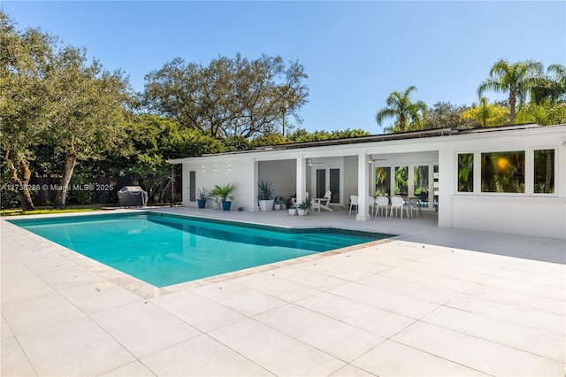 outdoor pool with ceiling fan, a patio, area for grilling, fence, and french doors