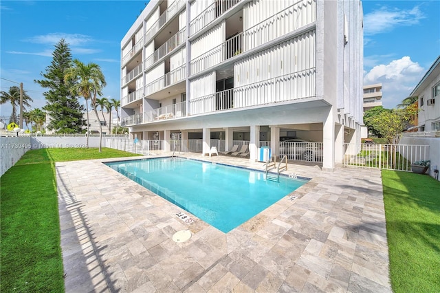 view of pool with a patio and a lawn