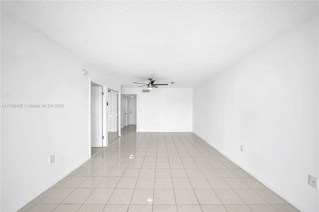 tiled empty room with a textured ceiling and ceiling fan