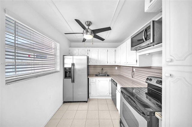 kitchen featuring sink, light tile patterned floors, ceiling fan, stainless steel appliances, and white cabinets