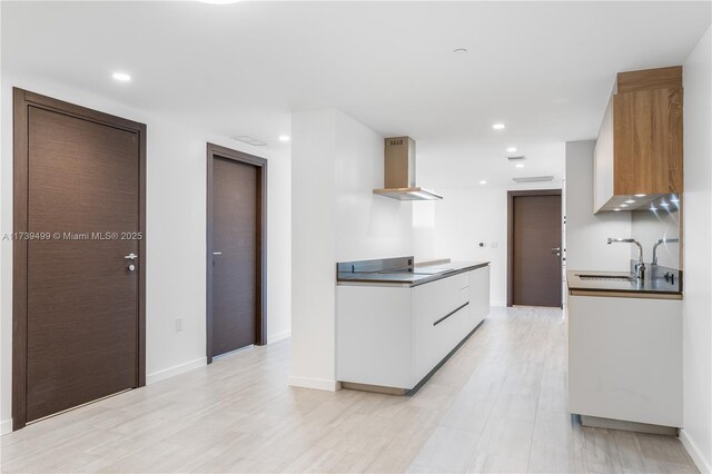 kitchen featuring built in microwave, stainless steel oven, a center island, light hardwood / wood-style floors, and white cabinets