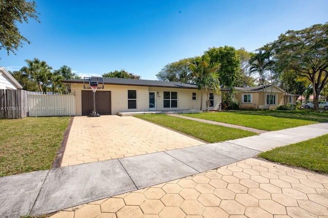 single story home featuring an attached garage, fence, decorative driveway, stucco siding, and a front lawn