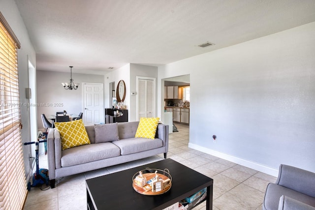 living area with visible vents, a notable chandelier, baseboards, and light tile patterned floors