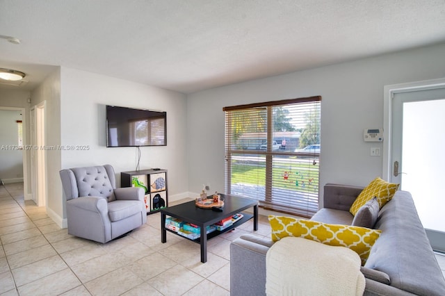 living room with a textured ceiling, baseboards, and light tile patterned floors