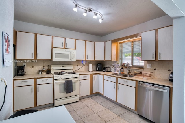 kitchen featuring white appliances, light countertops, a sink, and white cabinets