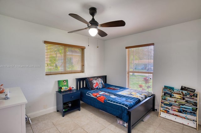 bedroom featuring multiple windows, ceiling fan, baseboards, and light tile patterned floors