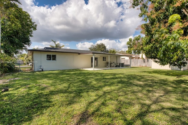 back of house featuring stucco siding, a patio area, fence, and a lawn