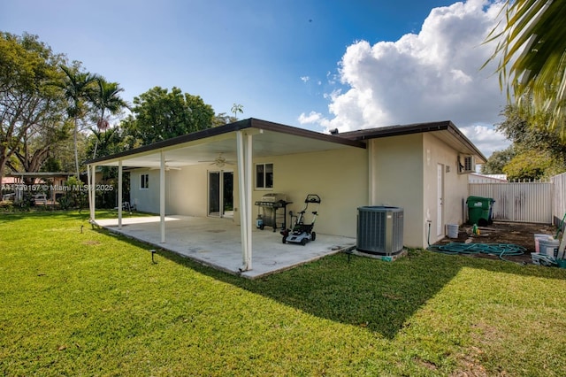 rear view of house featuring a fenced backyard, cooling unit, a ceiling fan, a yard, and stucco siding