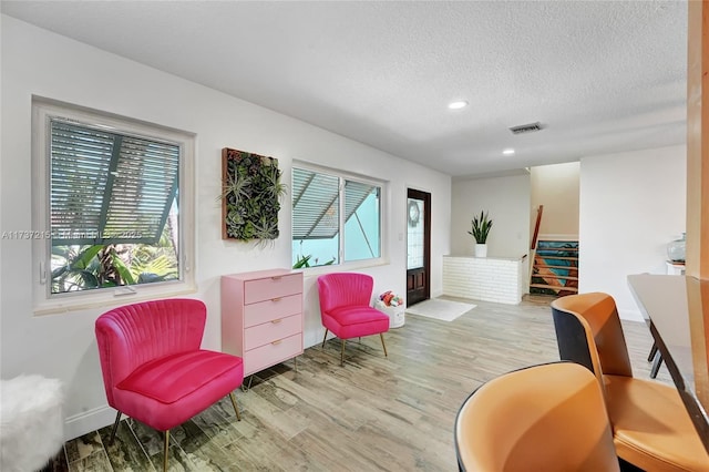 living area featuring light hardwood / wood-style flooring, a textured ceiling, and plenty of natural light