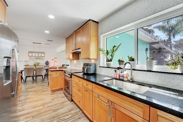 kitchen featuring appliances with stainless steel finishes, pendant lighting, sink, light hardwood / wood-style floors, and kitchen peninsula