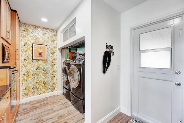 clothes washing area with separate washer and dryer and light hardwood / wood-style flooring