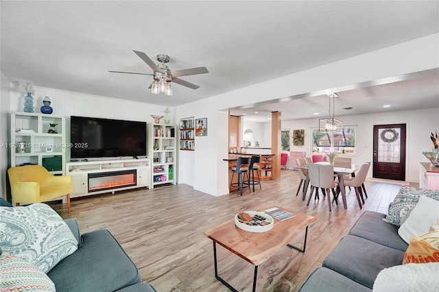 living room featuring ceiling fan, hardwood / wood-style floors, and a textured ceiling