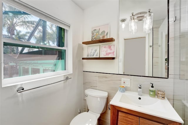 bathroom with vanity, toilet, and tile walls