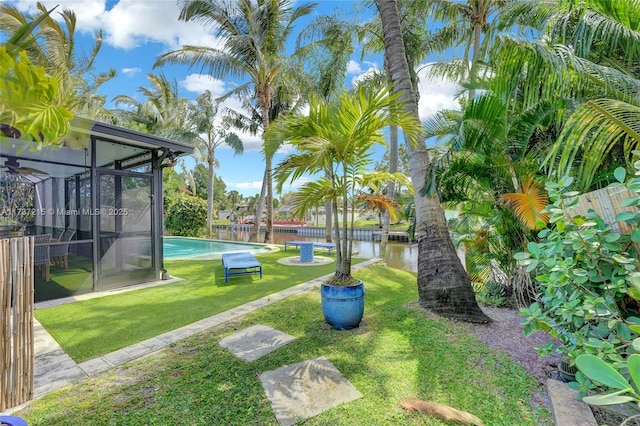 view of yard featuring a fenced in pool, a sunroom, and a water view