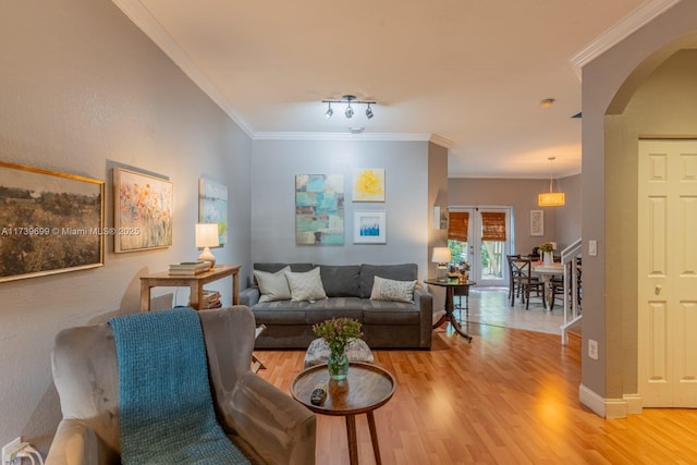 living room with crown molding, light wood-type flooring, and french doors