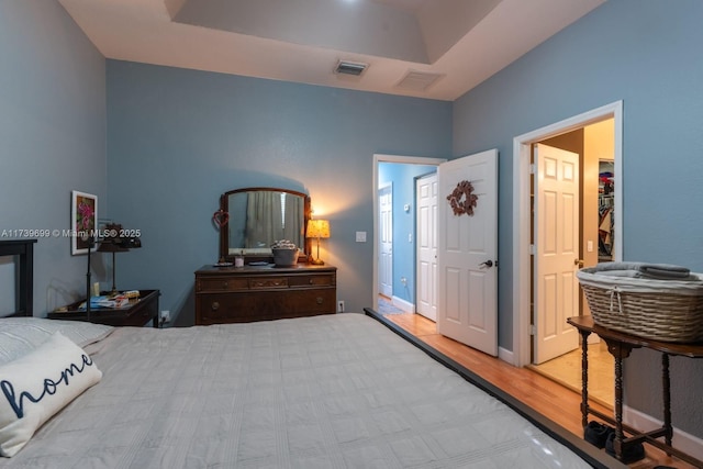 bedroom featuring a raised ceiling and light wood-type flooring