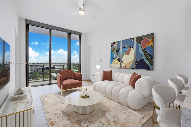 living room featuring floor to ceiling windows, ceiling fan, and light wood-type flooring