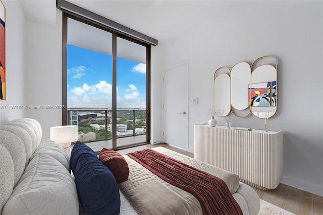 bedroom with access to outside, a wall of windows, and light hardwood / wood-style floors