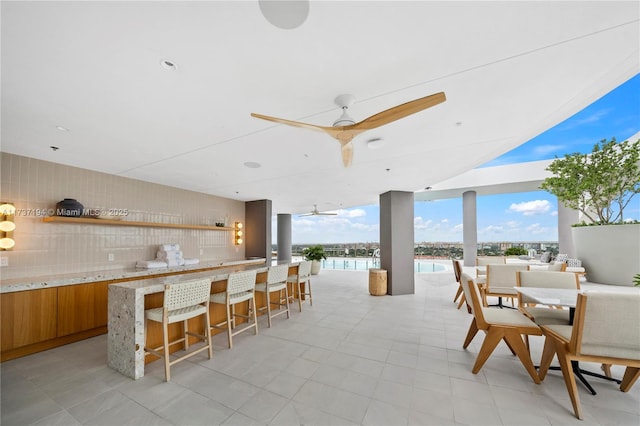 view of patio / terrace featuring a water view, ceiling fan, a kitchen bar, and floor to ceiling windows