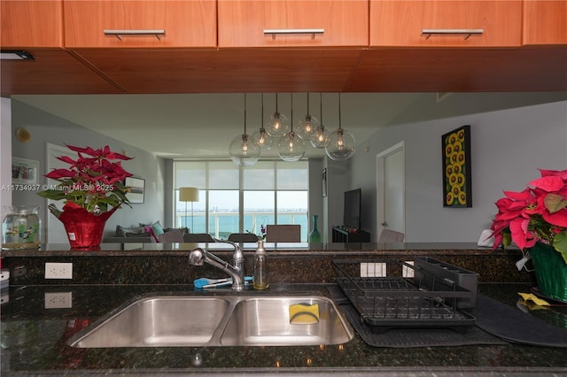 kitchen with pendant lighting, sink, and dark stone counters