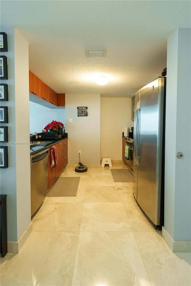 kitchen featuring stainless steel appliances, sink, and a textured ceiling