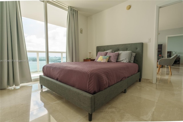 bedroom featuring a water view, a wall of windows, and access to exterior