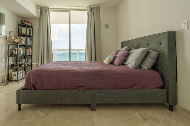 bedroom with a water view and a wall of windows