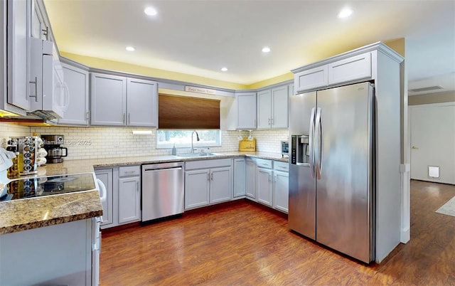 kitchen with tasteful backsplash, sink, dark wood-type flooring, and stainless steel appliances