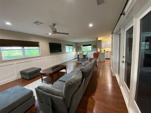 living room with dark hardwood / wood-style flooring and ceiling fan