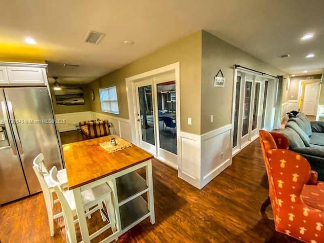 kitchen featuring white cabinetry, dark hardwood / wood-style floors, stainless steel refrigerator with ice dispenser, a kitchen bar, and french doors